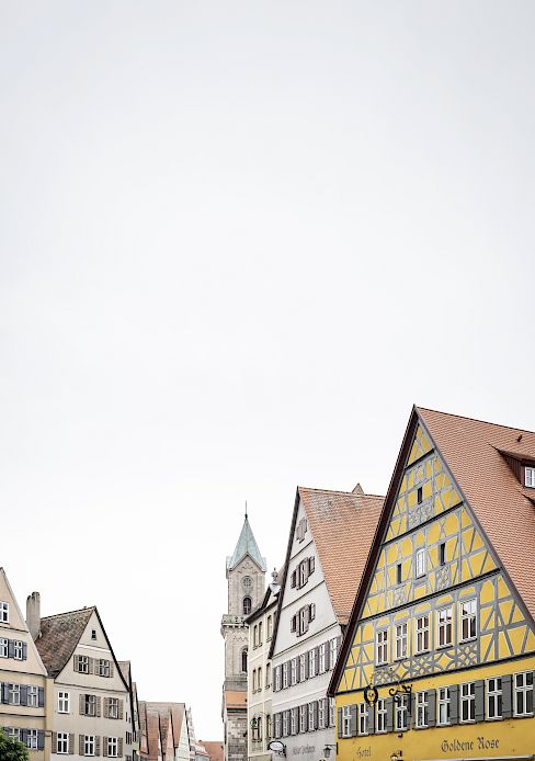 Historische Fachwerkhäuser und ein Kirchturm bei bewölktem Himmel in einer deutschen Stadt.